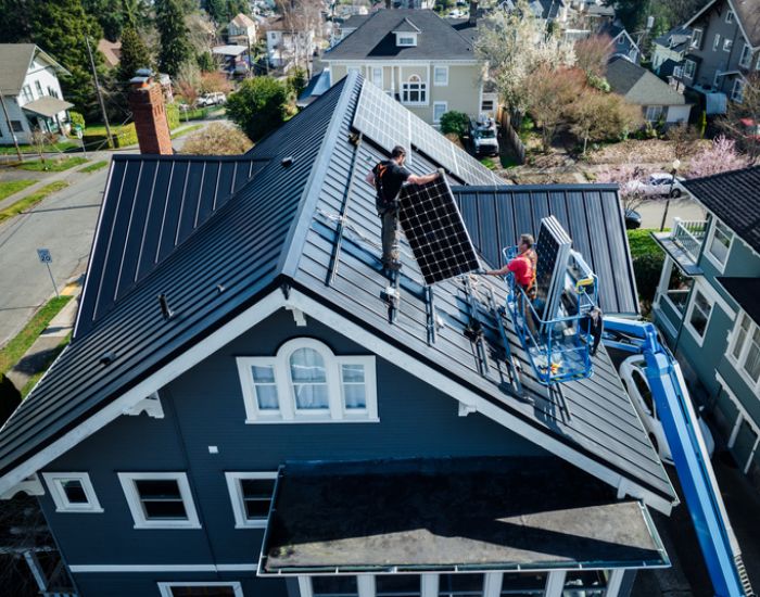 In DeKalb County, IL, a man works on a roof, installing a solar panel to harness solar energy.