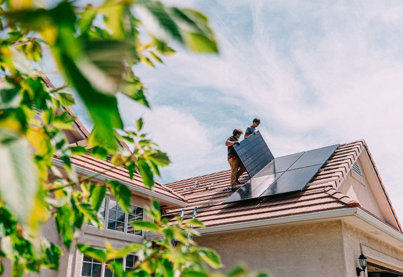 Residential solar panel installation in Chicago, IL, with workers on a tiled roof under a sunny sky