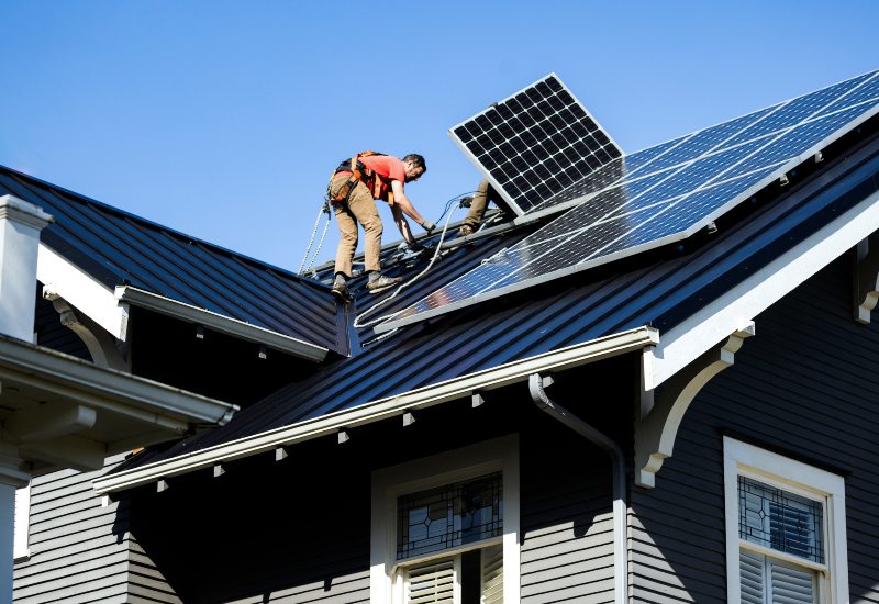 Workers securing solar panels on a home roof under clear skies for solar incentives in Chicago, IL